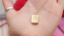 Load image into Gallery viewer, Dainty Thrills gold necklace with a dainty pendant featuring a red gemstone held in a hand against a red background.