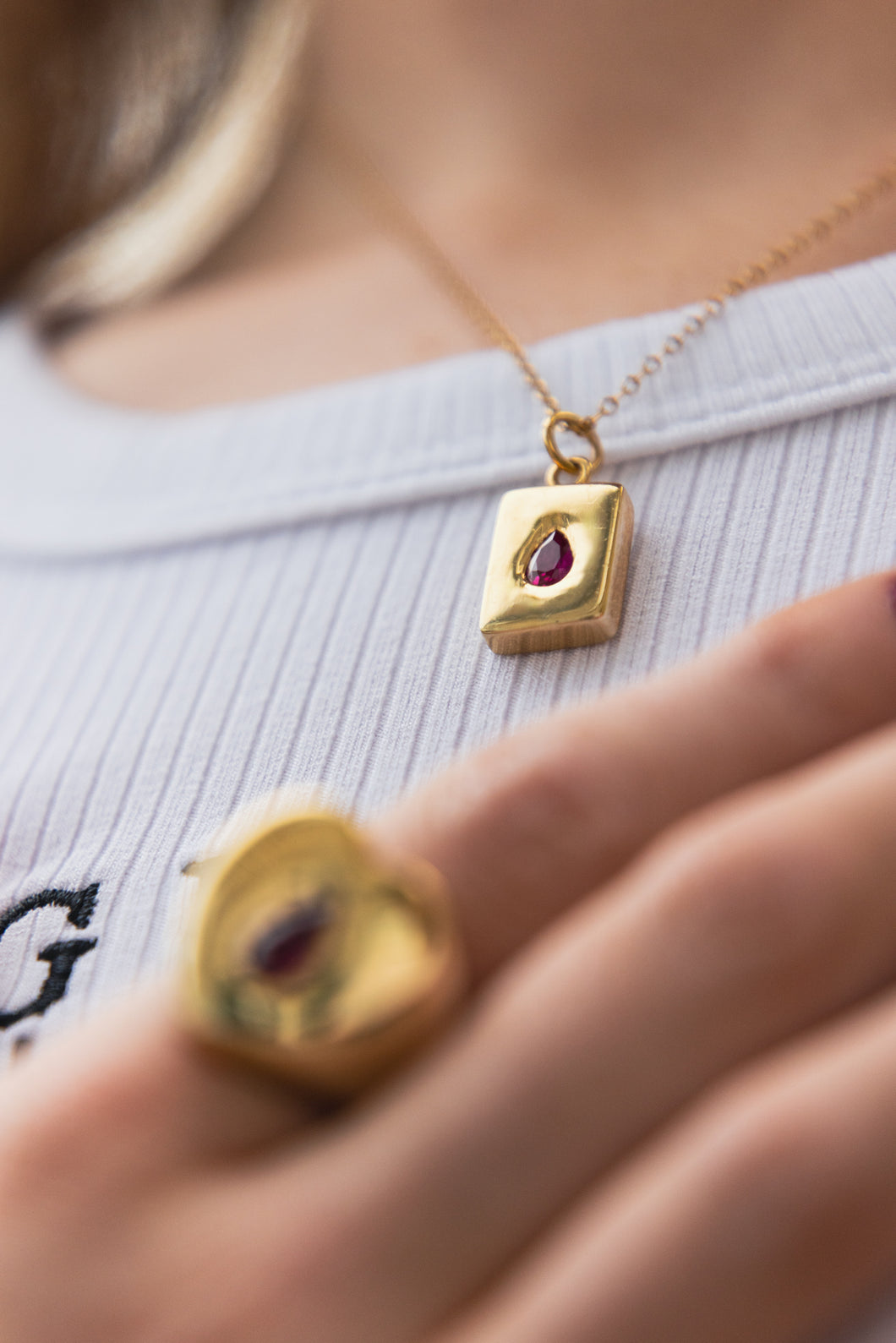 Dainty Thrills gold necklace with a dainty pendant featuring a red gemstone worn by a Gillian Magee the Founder. 